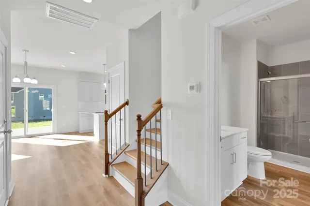 a view of a hallway with wooden floor and a bathroom
