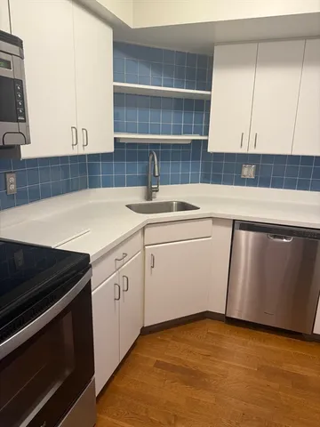 a view of kitchen with stove and white cabinets