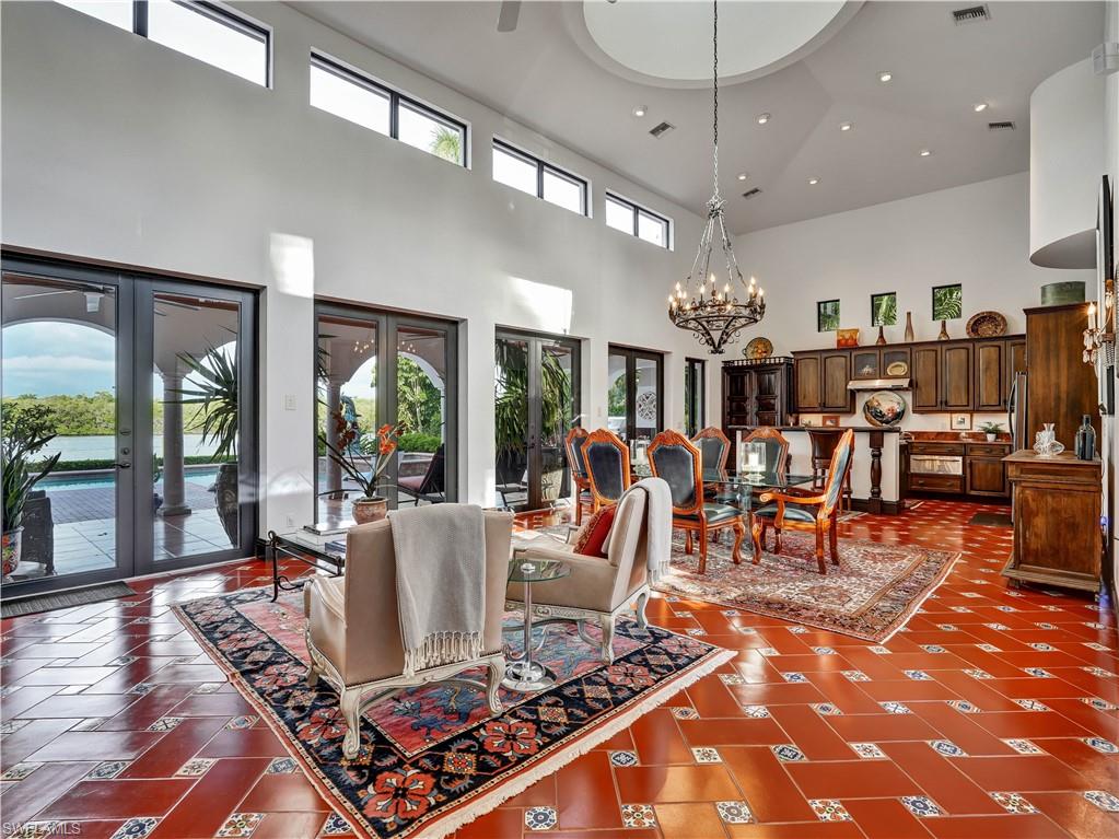 2535 Tarpon Road Naples, FL 34102 - Photo 7 of 50 Spacious great room featuring high vaulted ceilings, terracotta-style flooring with decorative inlays, a prominent double-door entry with an arched transom, and recessed lighting throughout
