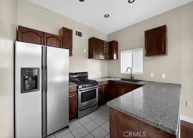 a kitchen with stainless steel appliances granite countertop a refrigerator a stove and a sink with wooden floor