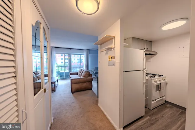 a living room with furniture a refrigerator and wooden floor