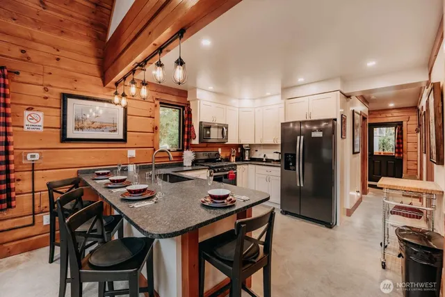 a kitchen with stainless steel appliances granite countertop a table chairs stove and refrigerator