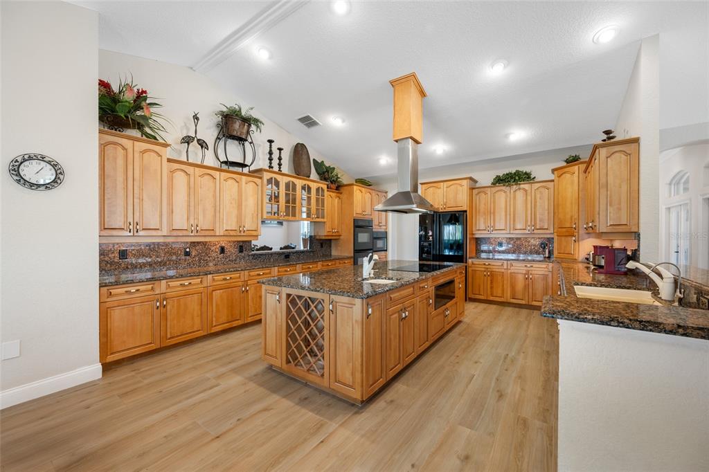 11939 Pasco Trails Boulevard Spring Hill, FL 34610 - Photo 31 of 61 a kitchen with stainless steel appliances granite countertop a lot of cabinets and wooden floor