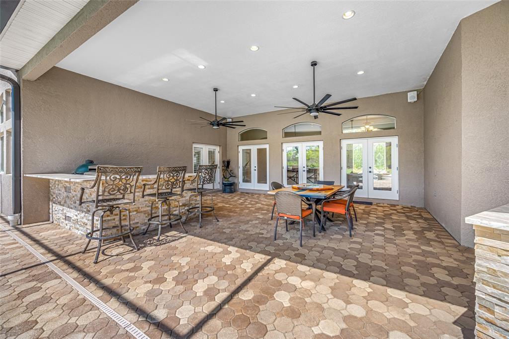 11939 Pasco Trails Boulevard Spring Hill, FL 34610 - Photo 50 of 61 a living room with lots of chairs a chandelier and a table
