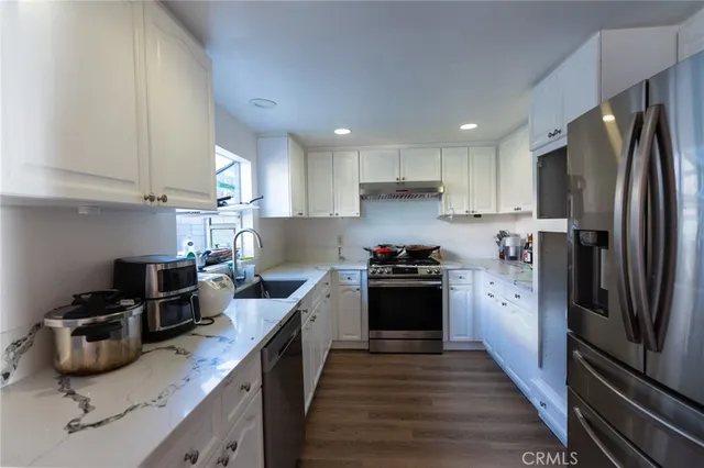a kitchen with granite countertop a refrigerator stove and sink