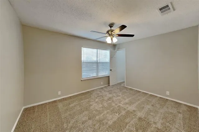 an empty room with windows and ceiling fan