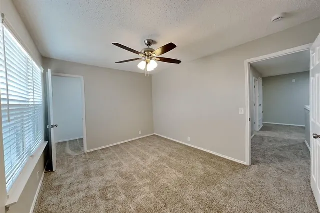 an empty room with chandelier fan and windows