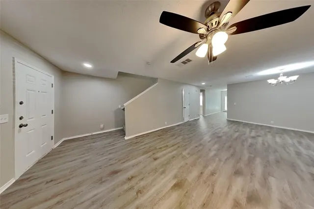 a view of an empty room with wooden floor and a ceiling fan