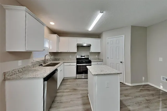 a kitchen with a stove top oven a sink a counter space and cabinets
