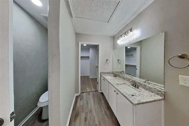 a bathroom with a granite countertop sink a toilet a mirror and shower