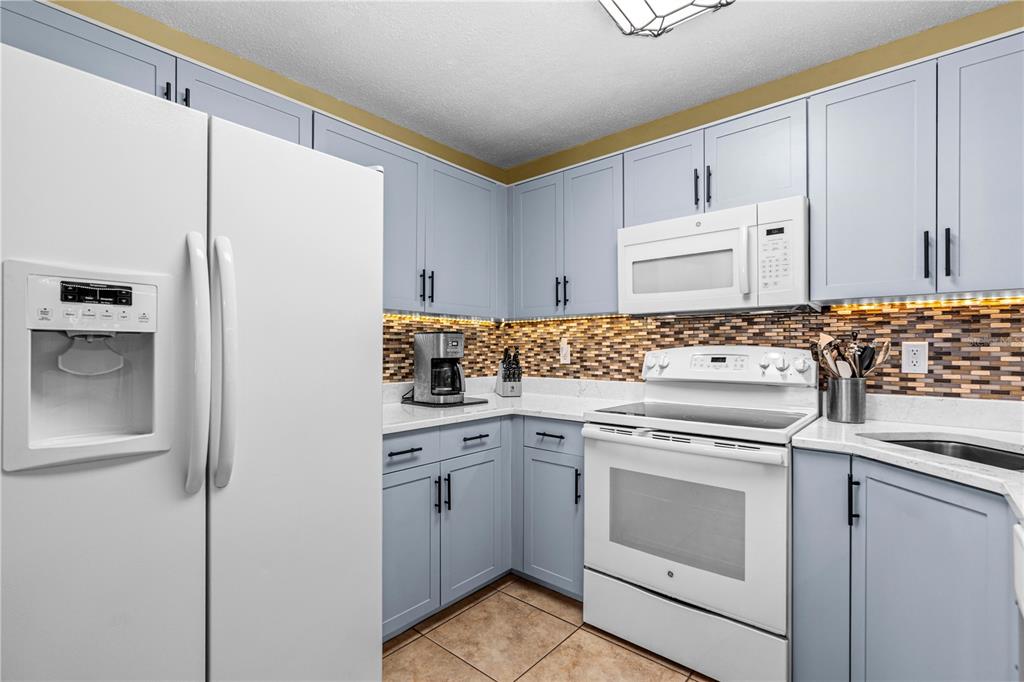 124 Rose Bank Road Daytona Beach, FL 32114 - Photo 15 of 43 a kitchen with white cabinets and white appliances