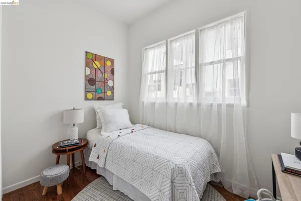 a bedroom with a bed a mirror and a window with wooden floor