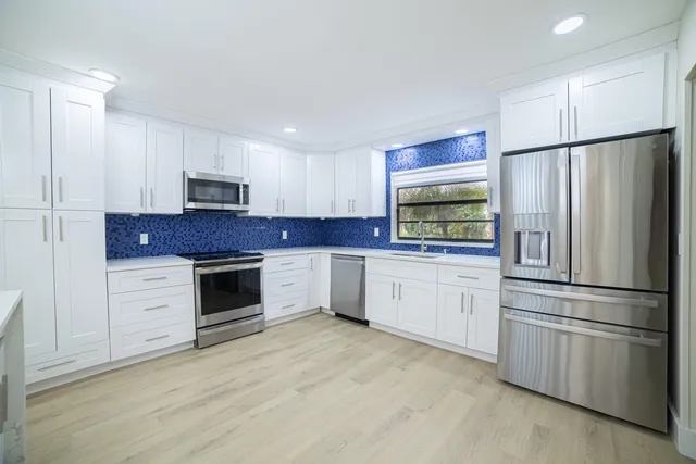 a kitchen with granite countertop white cabinets and stainless steel appliances