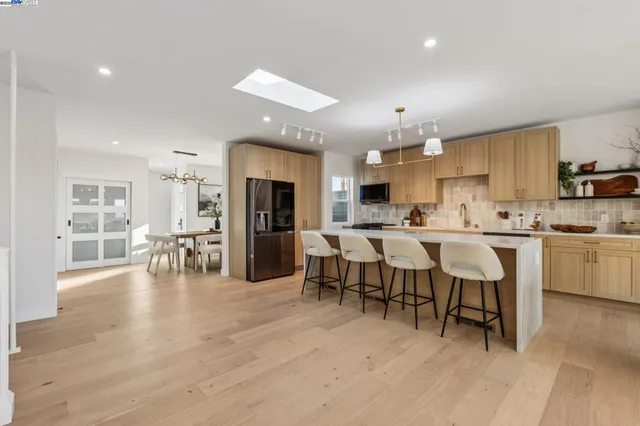 a kitchen with stainless steel appliances kitchen island granite countertop a table chairs microwave and sink