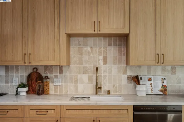 a large kitchen with a large counter top space a sink stainless steel appliances and cabinets