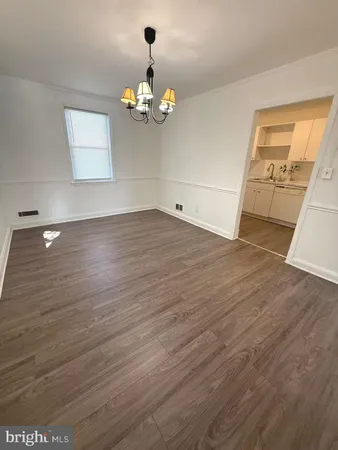 a view of a livingroom with wooden floor and a kitchen