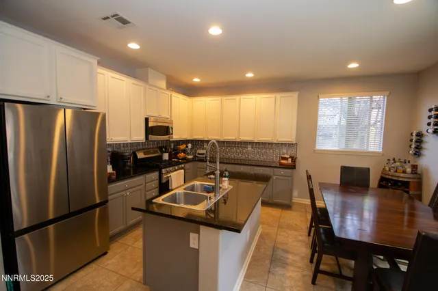 a kitchen with stainless steel appliances granite countertop a refrigerator a stove a dining table and chairs