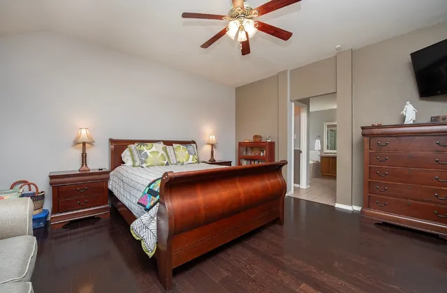 a bedroom with a bed and a flat tv screen on dresser