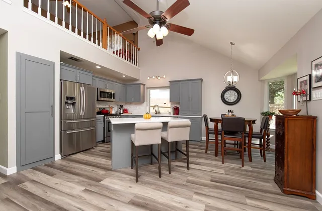 a kitchen with stainless steel appliances kitchen island granite countertop a table chairs sink and cabinets
