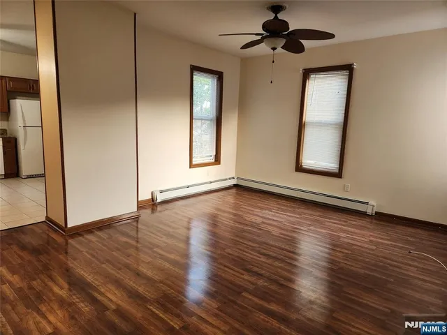 an empty room with wooden floor cabinet and windows
