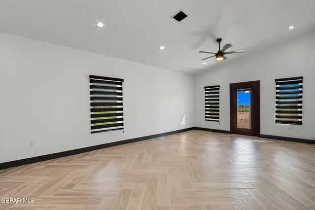 a view of an empty room with a window and wooden floor