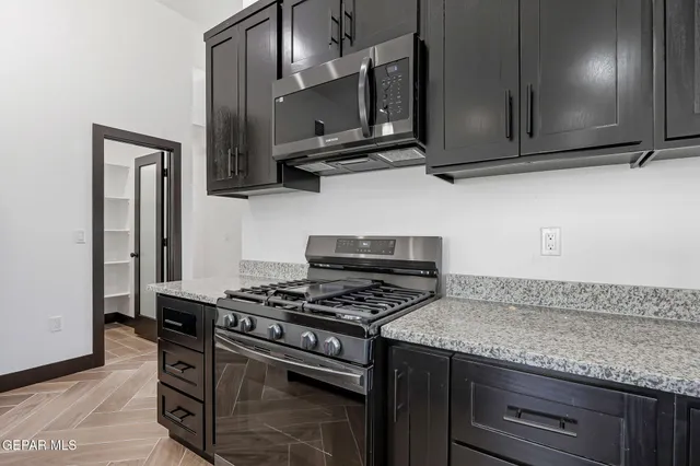 a kitchen with granite countertop a stove and a microwave