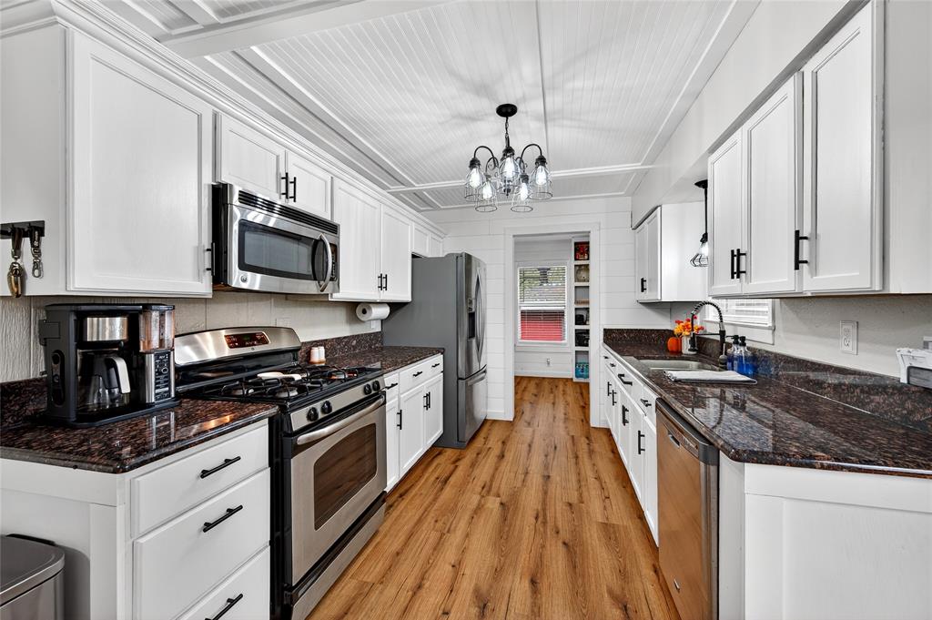 1115 Oak Ridge Drive Denison, TX 75020 - Photo 13 of 32 a kitchen with stainless steel appliances granite countertop a stove top oven a sink dishwasher and a refrigerator with wooden floor