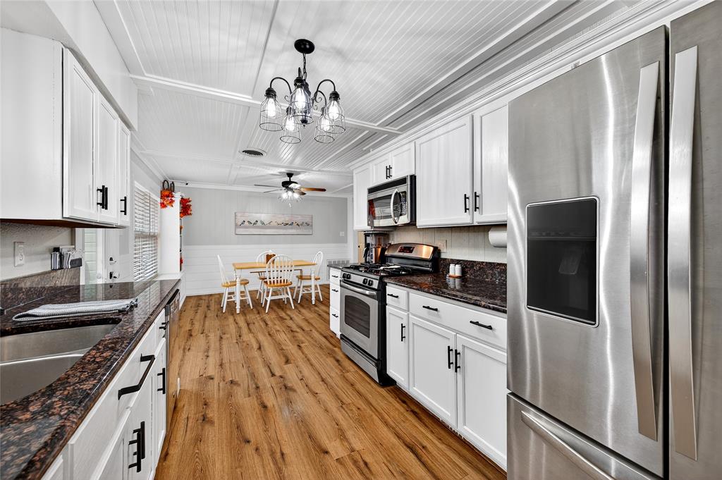 1115 Oak Ridge Drive Denison, TX 75020 - Photo 15 of 32 a kitchen with stainless steel appliances granite countertop a refrigerator a stove top oven a sink dishwasher and white cabinets with wooden floor