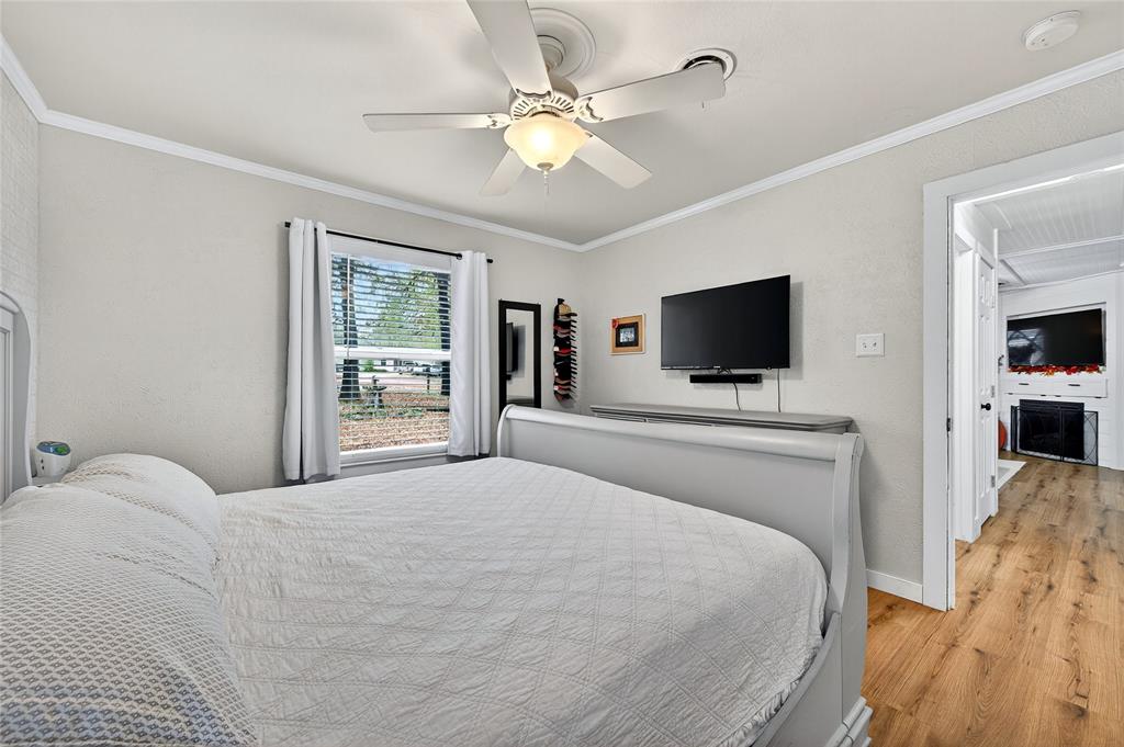 1115 Oak Ridge Drive Denison, TX 75020 - Photo 21 of 32 a bedroom with a large bed a flat tv screen and a ceiling fan