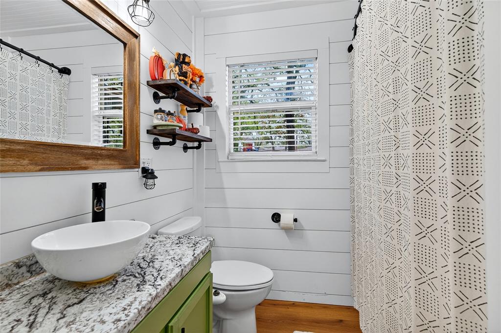 1115 Oak Ridge Drive Denison, TX 75020 - Photo 23 of 32 a bathroom with a granite countertop toilet sink and mirror