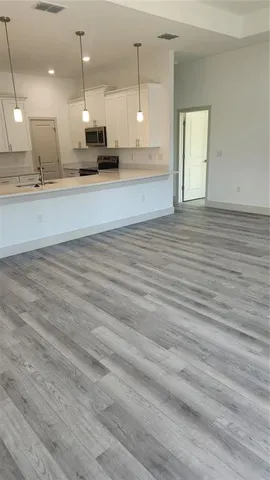 an open kitchen with kitchen island white cabinetry and wooden floor