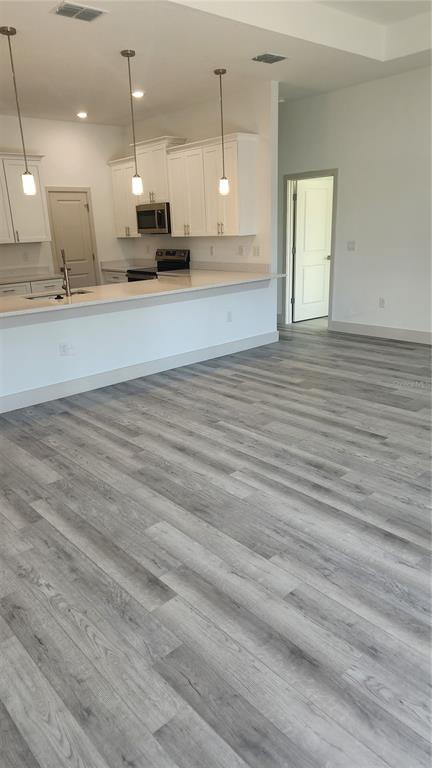 23469 Roscoe Avenue Punta Gorda, FL 33980 - Photo 7 of 26 an open kitchen with kitchen island white cabinetry and wooden floor