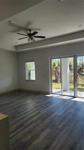 a view of an empty room with a window and wooden floor