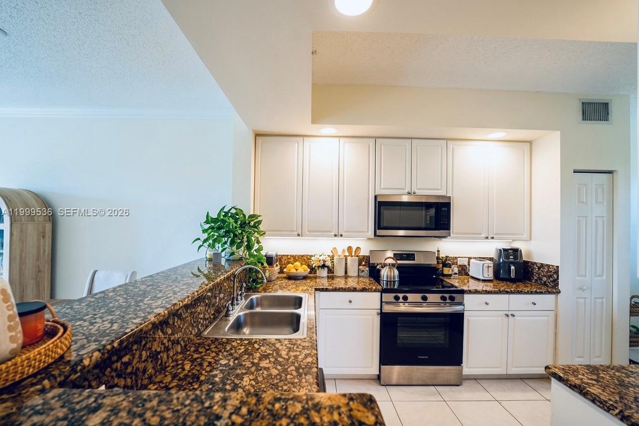 26 Royal Palm Way, Unit 304 Boca Raton, FL 33432 - Photo 8 of 38 a kitchen with granite countertop a stove and a refrigerator