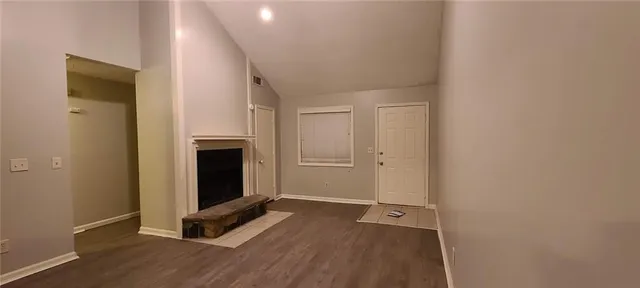 a view of an empty room with wooden floor and a fireplace