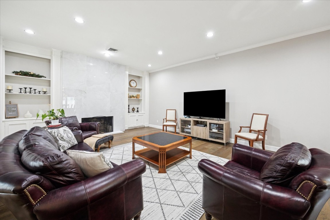 242 Vanderpool Lane Houston, TX 77024 - Photo 19 of 45 This spacious living room features a cozy fireplace, ceramic tile surround, built-in shelving, and modern recessed lighting.