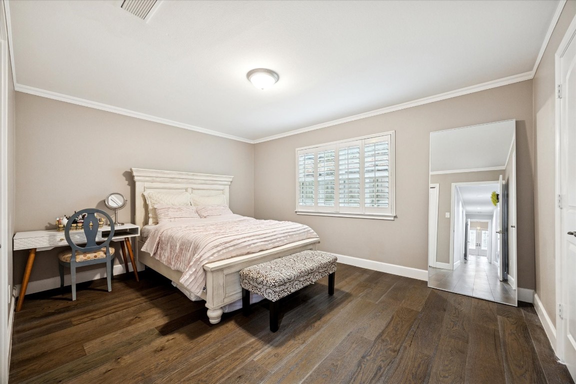 242 Vanderpool Lane Houston, TX 77024 - Photo 28 of 45 This inviting bedroom features warm wood flooring, a cozy bed, and soft neutral walls. A large window with shutters brings in natural light, and there's a stylish vanity for added convenience.