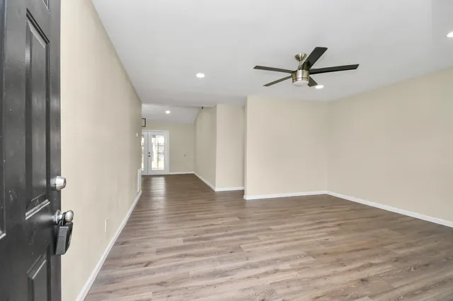 a view of a hallway with wooden floor and a ceiling fan