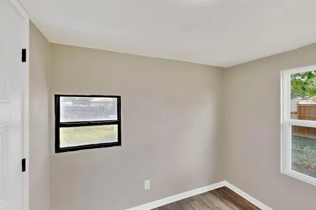 a view of an empty room with a window and a small kitchen