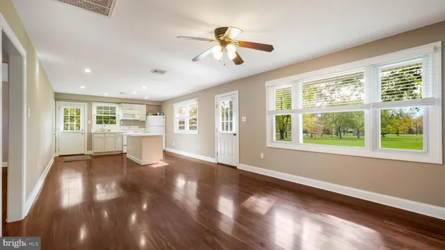 a view of an empty room with a window and wooden floor