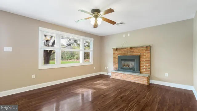 a view of an empty room with window fireplace and wooden floor