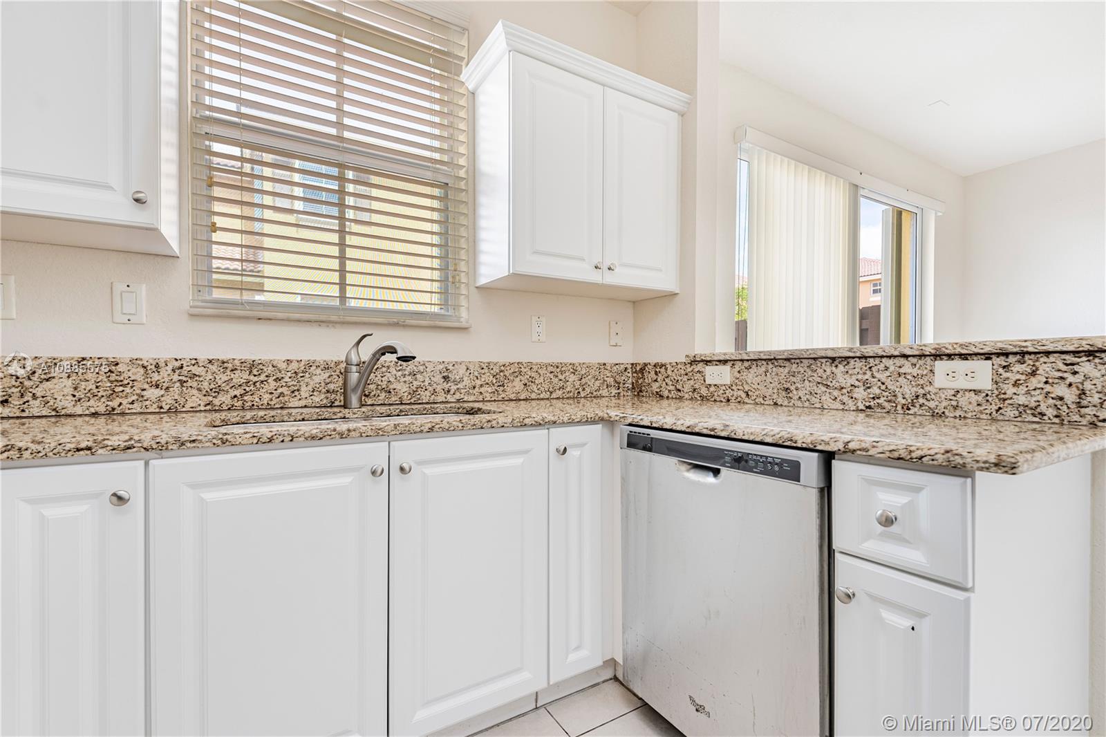 11926 Southwest 152nd Place Miami, FL 33196 - Photo 19 of 48 a kitchen with granite countertop white cabinets and white appliances