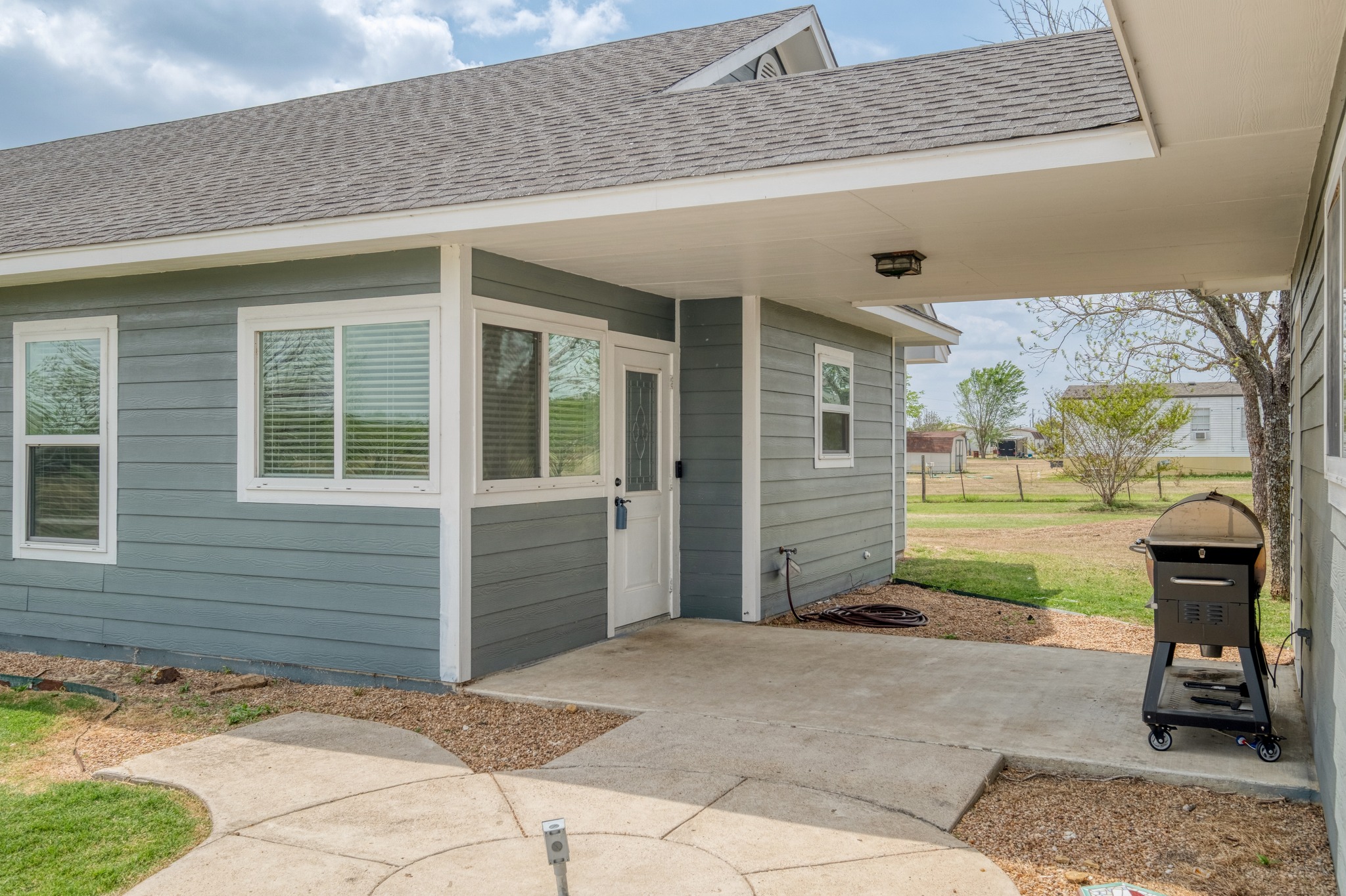 2950 County Road 484 Elgin, TX 78621 - Photo 5 of 25 Doorway to property featuring a shingled roof, a patio area, and a yard