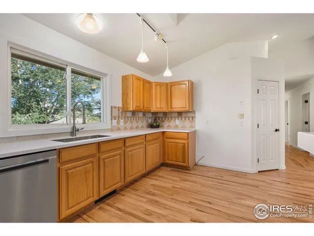 a kitchen with stainless steel appliances kitchen island granite countertop a stove top oven a sink dishwasher a dining table and chairs with wooden floor