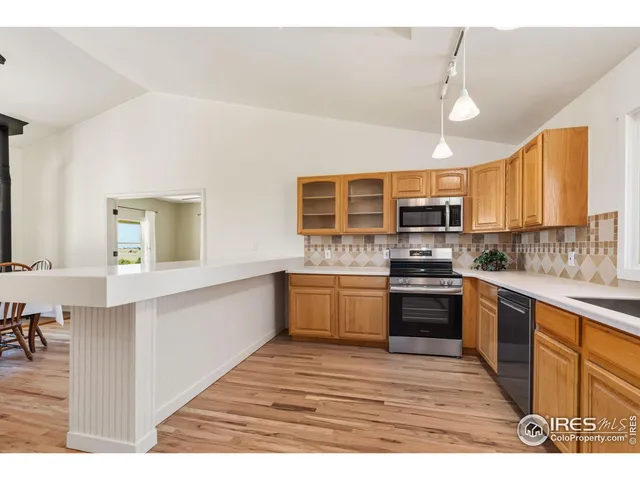a dining room with wooden floor a chandelier a glass table and chairs
