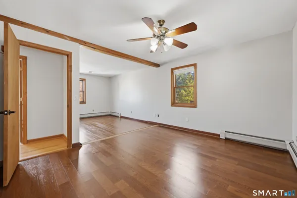 an empty room with wooden floor chandelier fan and windows