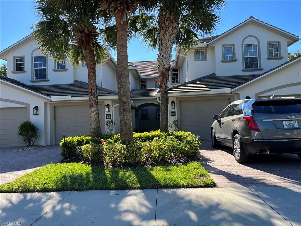 6809 Ascot Drive, Unit 202 Naples, FL 34113 - Photo 23 of 38 a front view of a house with a garden and a yard