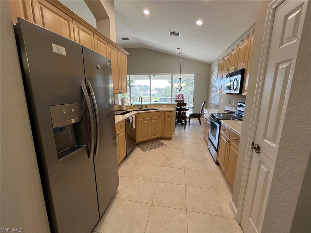 6809 Ascot Drive, Unit 202 Naples, FL 34113 - Photo 6 of 38 a kitchen with refrigerator and furniture