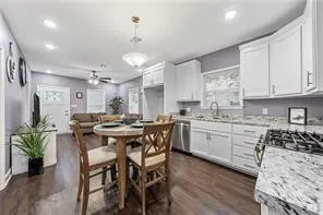 a kitchen with stainless steel appliances kitchen island granite countertop a table chairs sink and cabinets