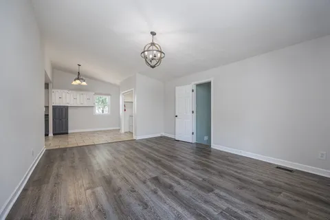 an empty room with wooden floor ceiling fan and windows